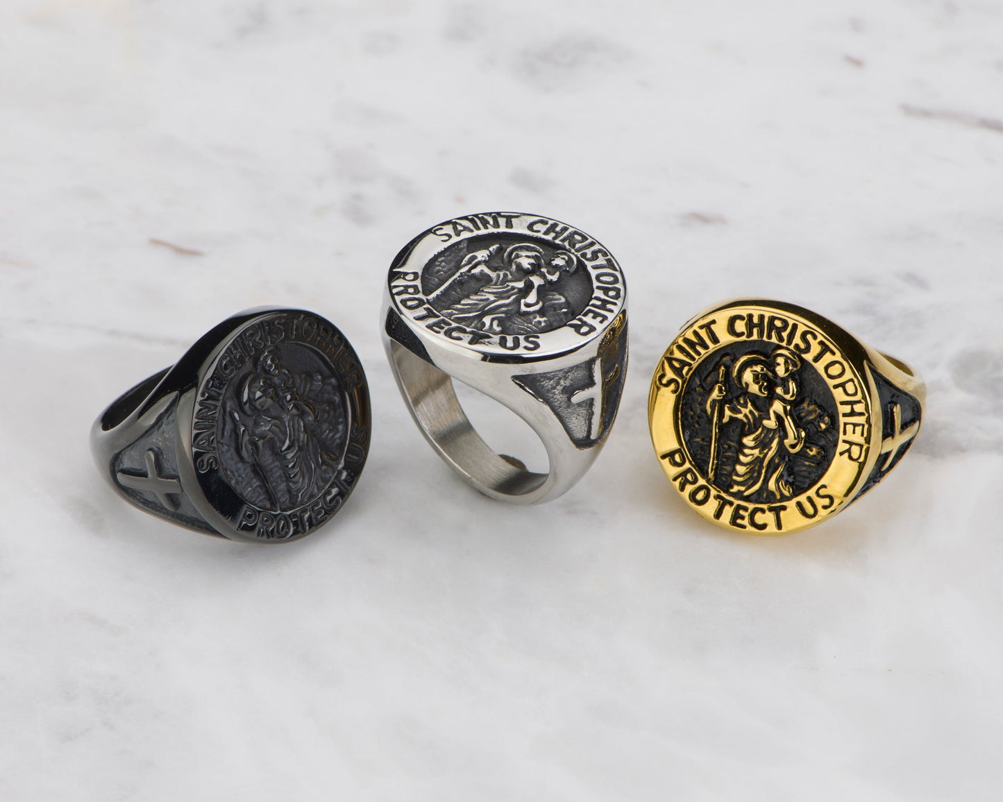 Three rings with religious designs on a marble surface