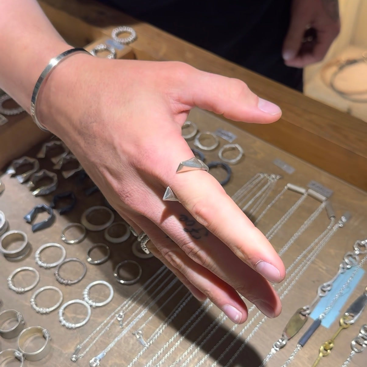 Hand wearing a silver ring on a display of jewelry components
