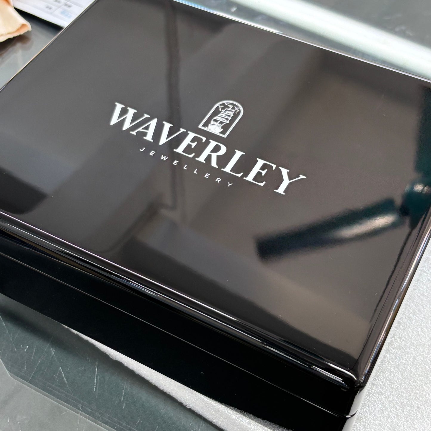 Black jewelry box with 'Waverley' branding on a reflective surface.