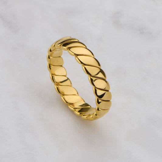 Gold ring with braided design on a light gray background