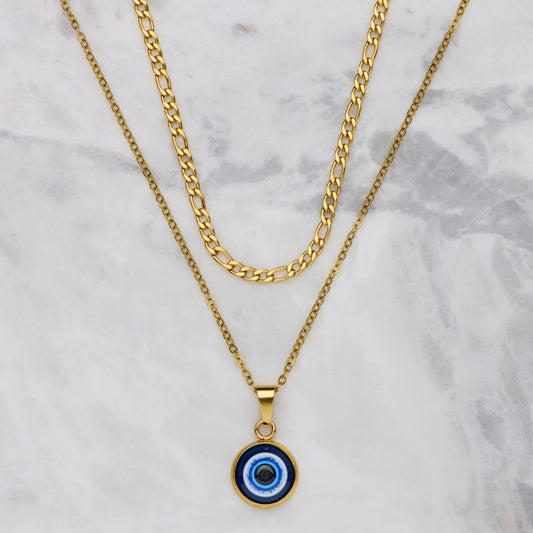 Gold necklace with a blue evil eye pendant on a marble background