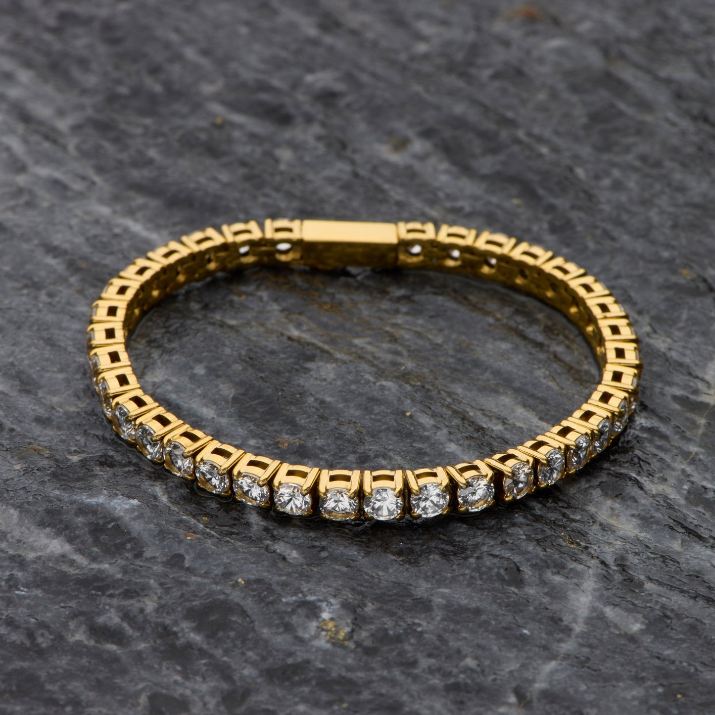 Gold bracelet with diamonds on a dark stone surface