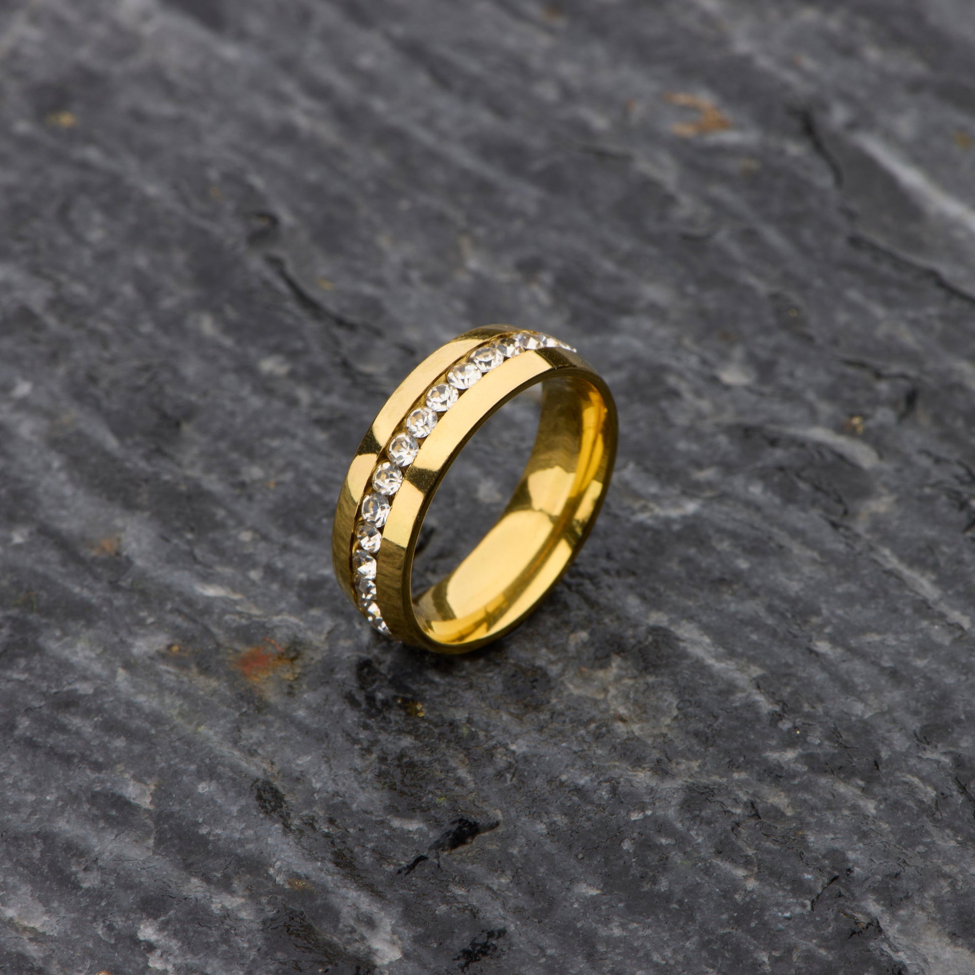 Gold ring with embedded stones on a dark stone surface