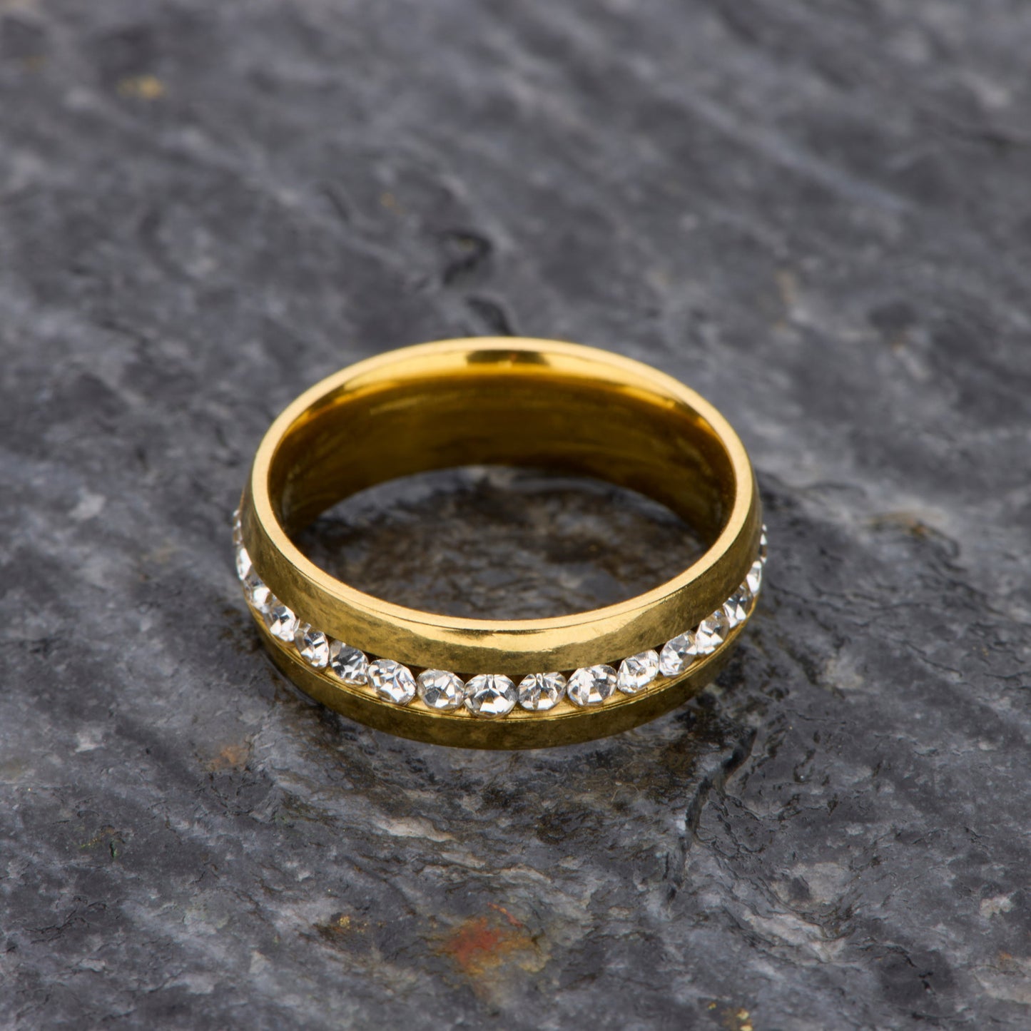 Gold ring with embedded diamonds on a textured stone surface