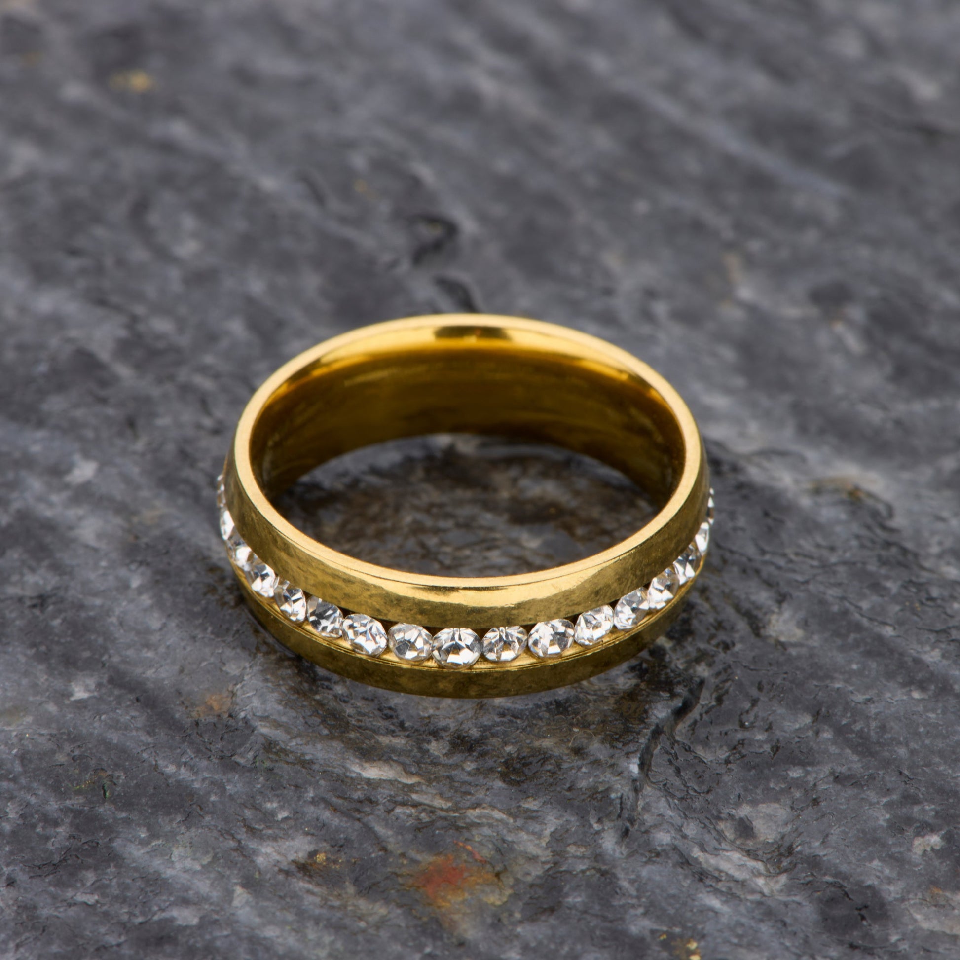 Gold ring with embedded diamonds on a textured stone surface