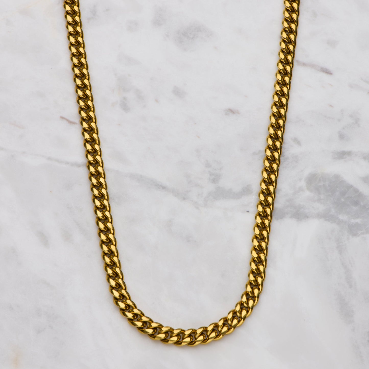 Gold chain necklace on a marble surface