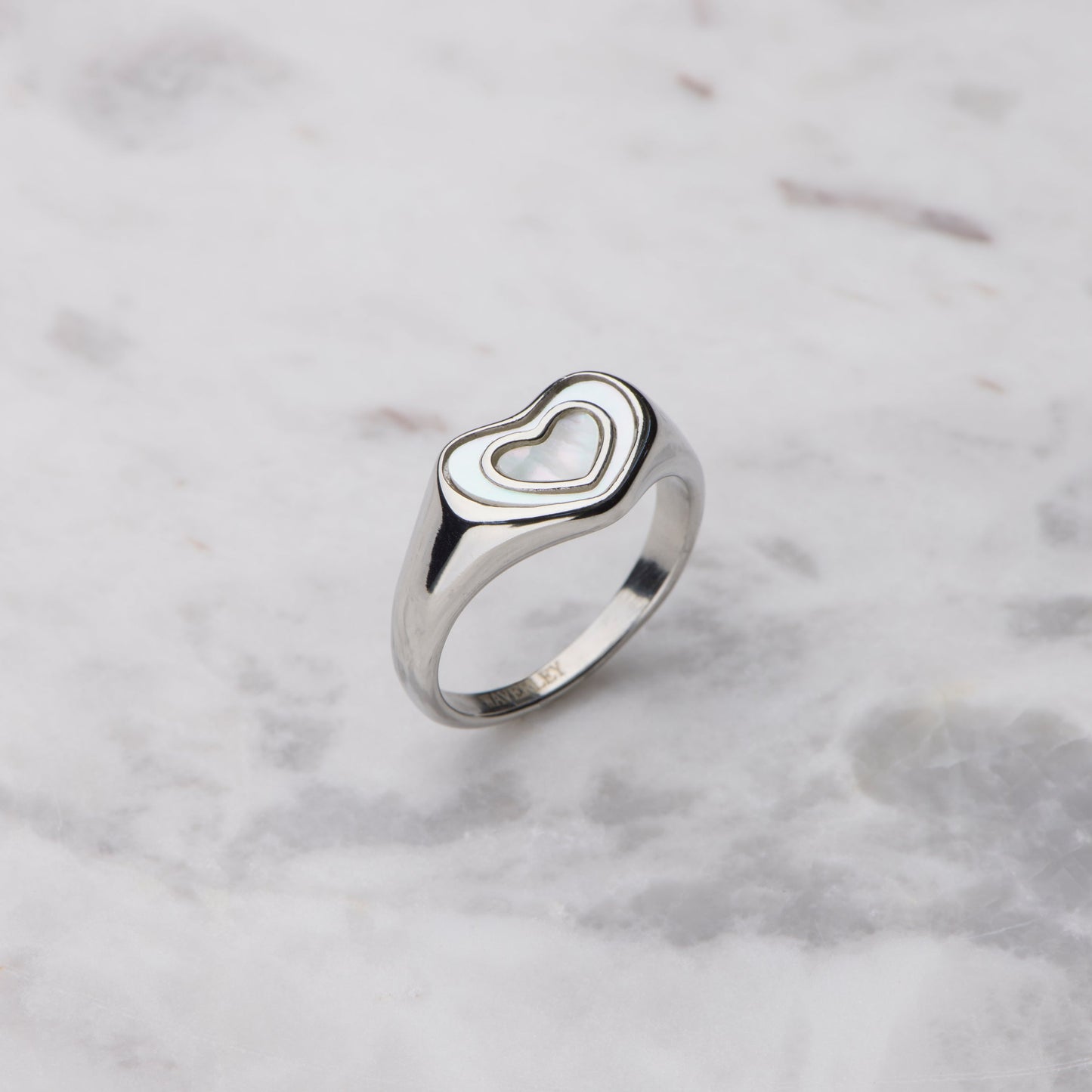 Silver heart-shaped ring on a marble surface