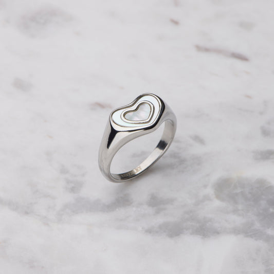 Silver heart-shaped ring on a marble surface