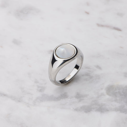 Silver ring with a central mother of pearl on a marble surface