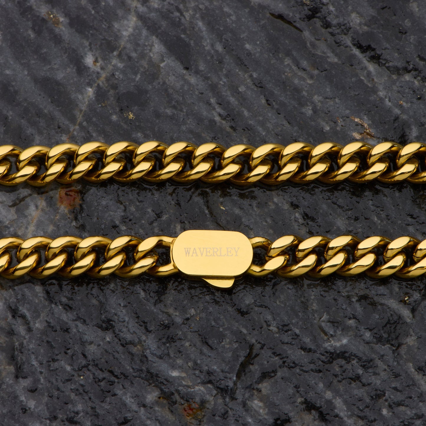Gold chain bracelet with a visible brand tag on a dark stone surface
