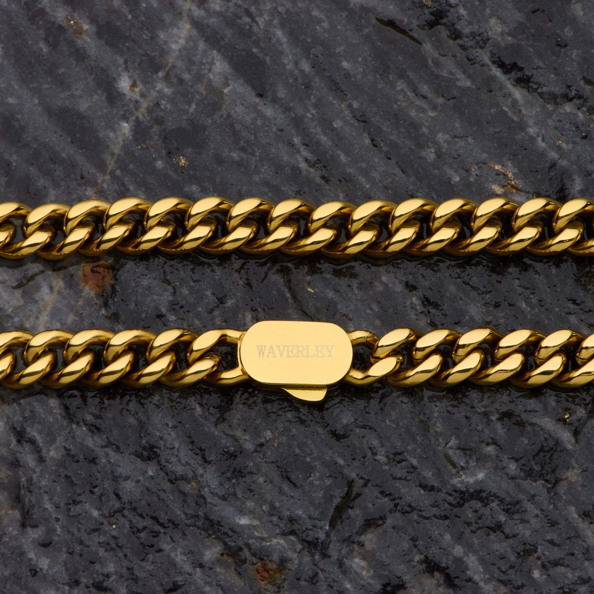 Gold chain bracelet with a visible brand tag on a dark stone surface