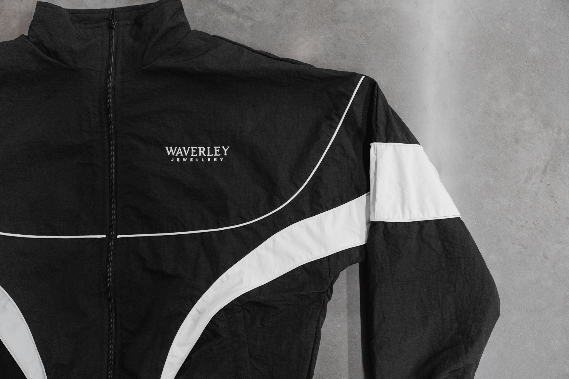 Black jacket with white accents and 'Waverley' branding on a grey background