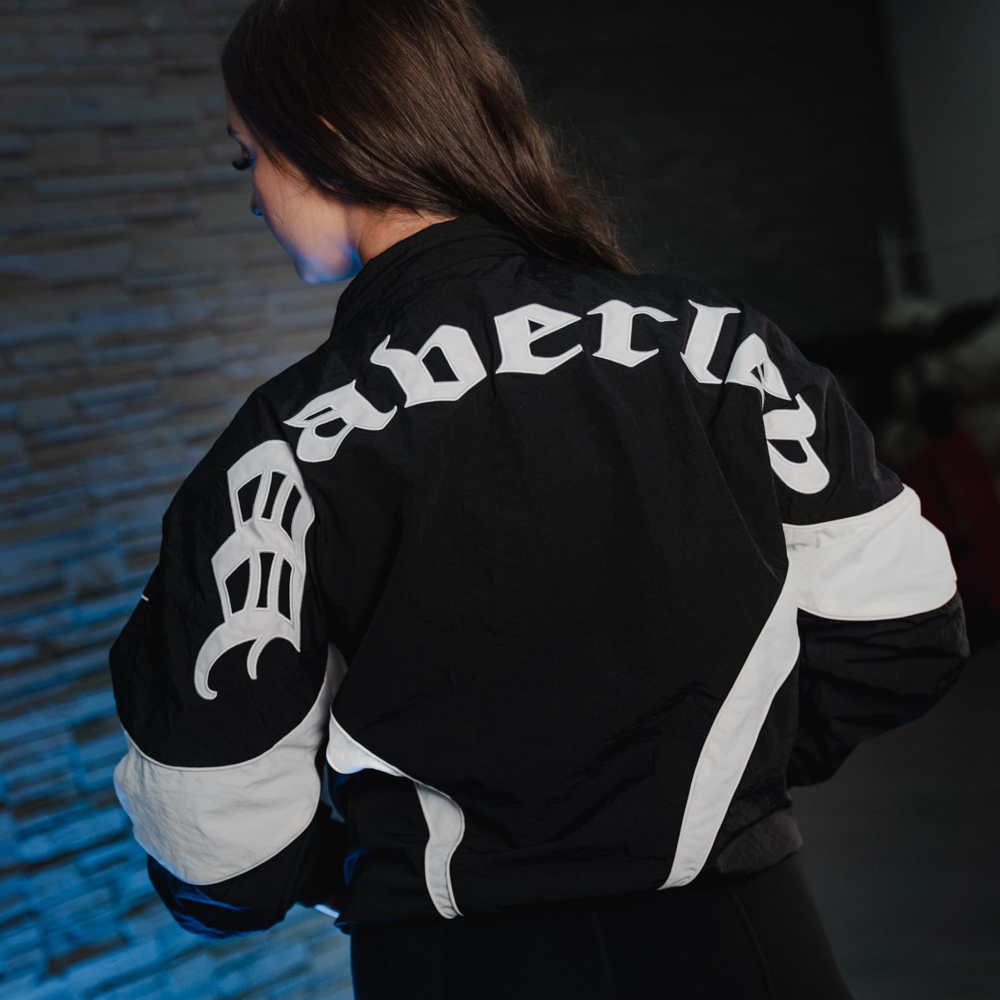 Female wearing a black and white jacket with 'Waverley' branding against a dark background.