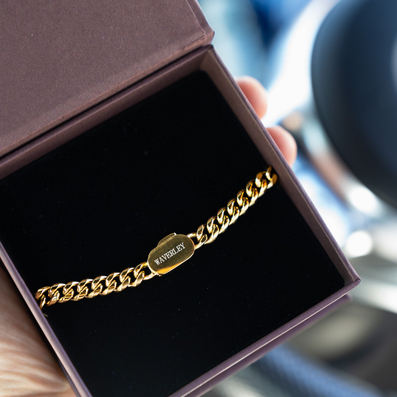 Gold bracelet in a jewelry box held by a hand with a blurred background