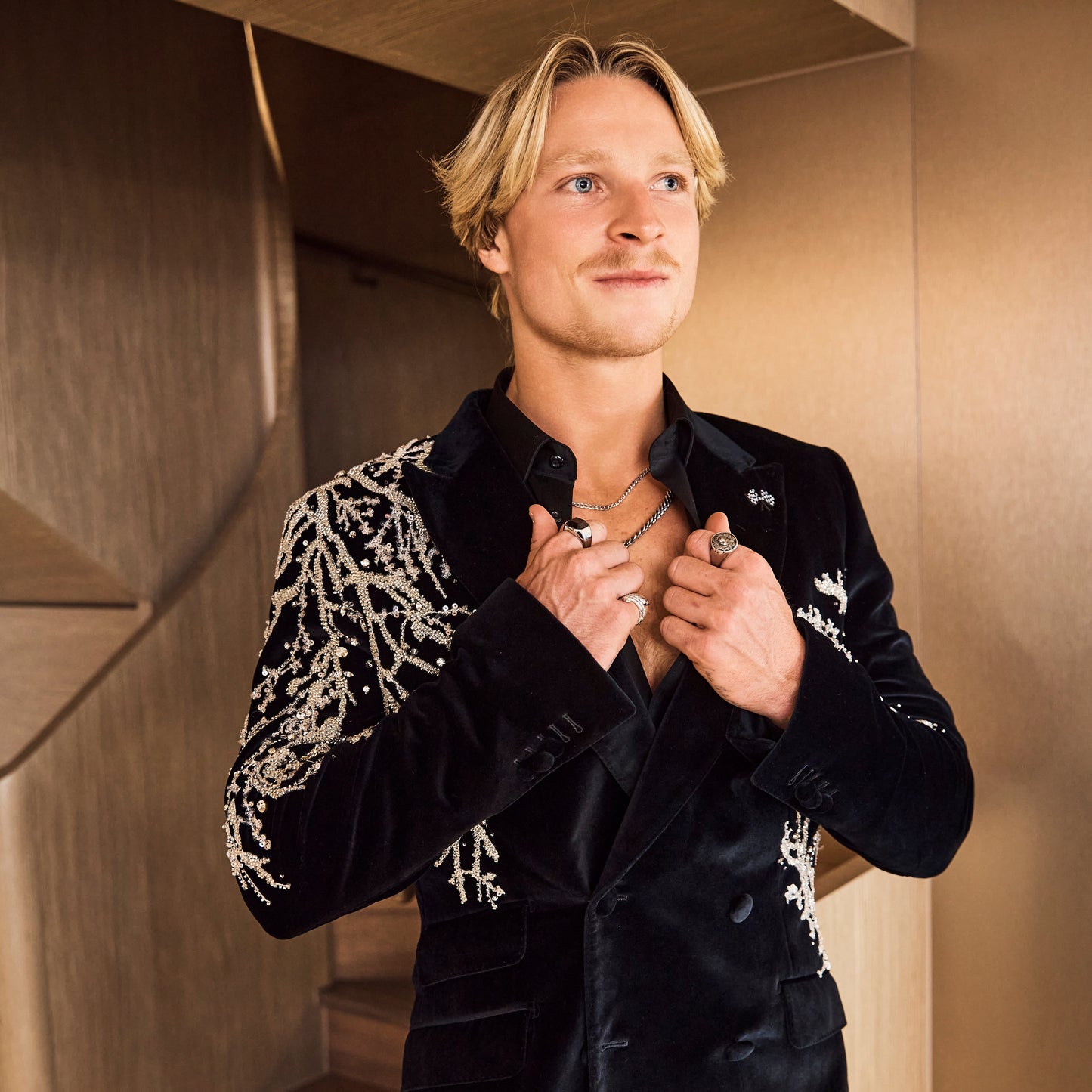 Man wearing a black jacket with white patterns in an indoor setting