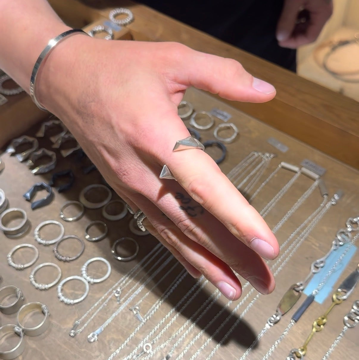 Hand wearing a ring with metal components on a table
