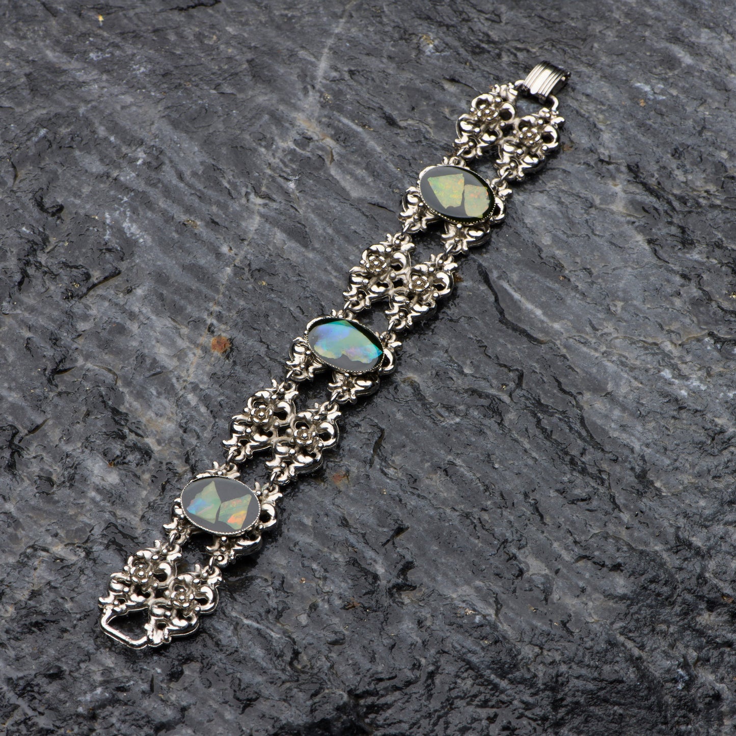 Silver bracelet with opal stones on a dark stone surface