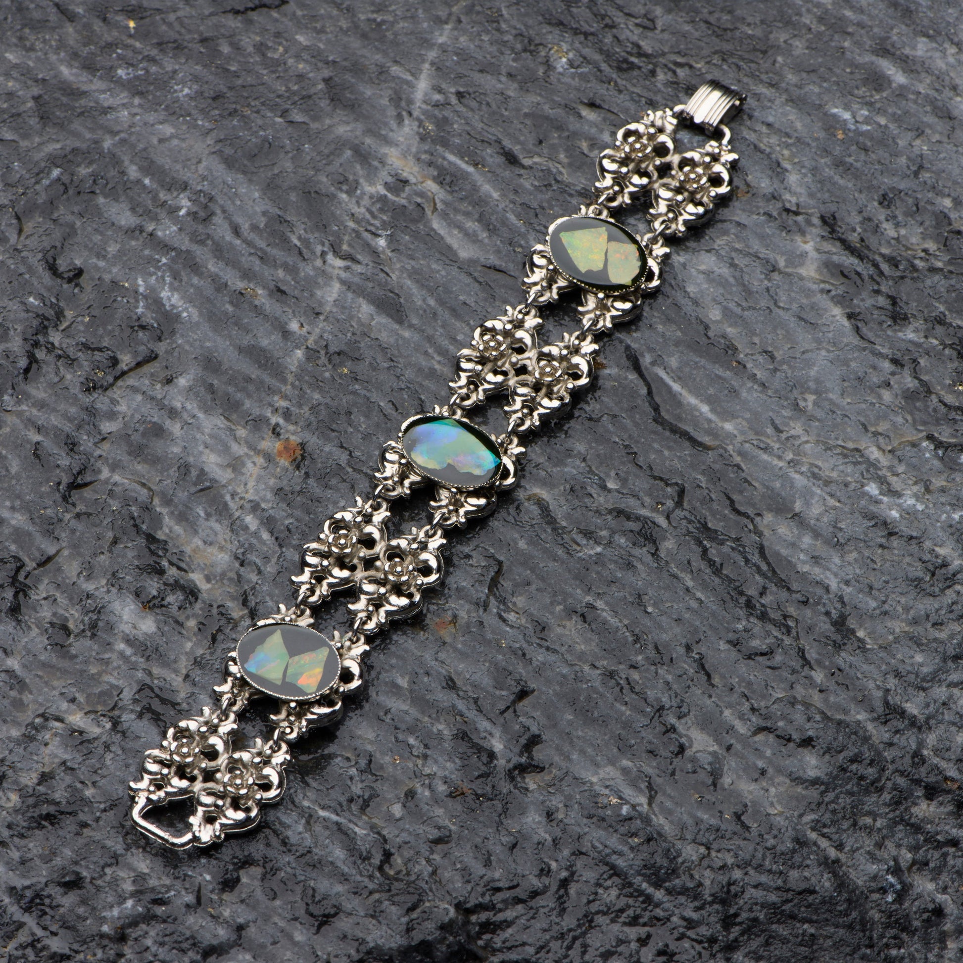 Silver bracelet with opal stones on a dark stone surface