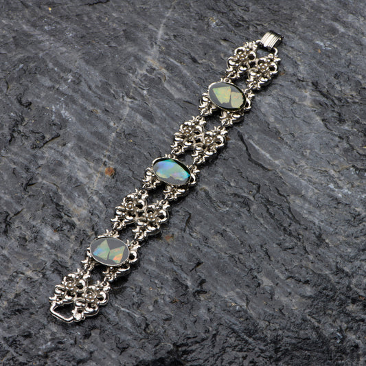 Silver bracelet with opal stones on a dark stone surface