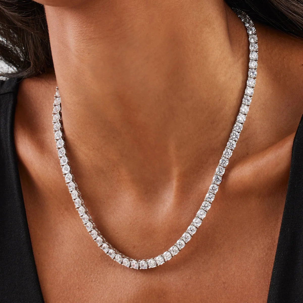 Close-up of a diamond necklace on a person wearing a black top.