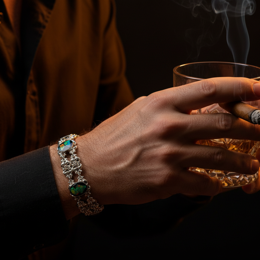Hand holding a glass of whiskey with a lit cigarette, wearing a decorative bracelet.