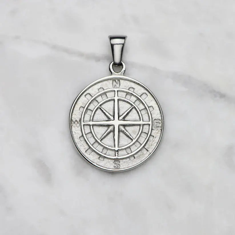 Silver compass pendant on a light gray background