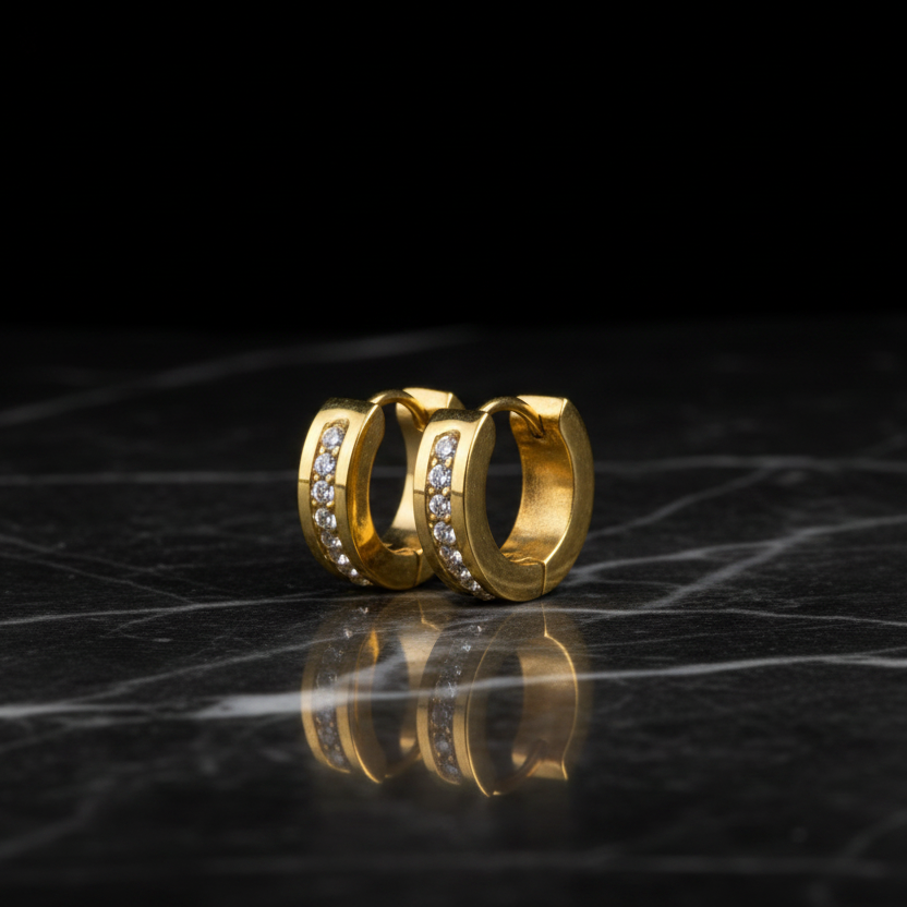 Gold hoop earrings with embedded stones on a reflective black surface