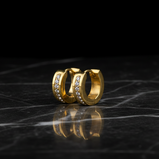 Gold hoop earrings with embedded stones on a reflective black surface
