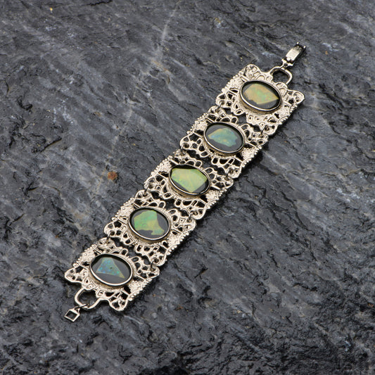 Bracelet with green gemstones on a dark stone surface